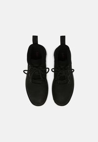 Black lace-up shoes with a smooth leather upper, a slip-on design, and fabric accents at the collar, featuring a textured surface.