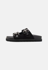 Sandali a scivolo in suede nero con due cinture regolabili in argento, suola in gomma con un motivo texturizzato e design piatto.