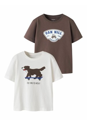 Deux t-shirts enfants à manches courtes : un marron avec "OAK HILL" et un motif de tracteur, un blanc avec un chien sur un skateboard et le texte "IT'S TIME TO ROLL!".