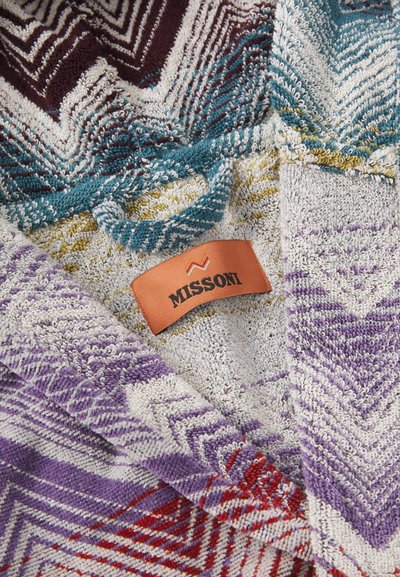 Spalvingas Missoni apsiaustas su zigzagų raštais purpurinės, raudonos, mėlynos ir baltos spalvų, pagamintas iš tekstūruotos medžiagos ir su odiniu etiketė.