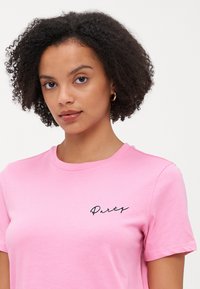 Rosa bomulls T-skjorte med korte ermer, med svart skrift "Party" broderi på venstre side. Glatt tekstur, rund halsdesign.