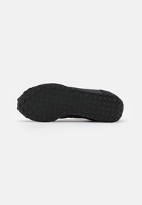 Semelle de chaussure noire avec des crampons en caoutchouc carrés couvrant uniformément toute la surface inférieure pour l'adhérence et la traction.