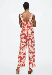 Květinový overal v červené a bílé barvě, s širokými nohavicemi a hlubokým výstřihem na zádech. Má výrazné květinové vzory a zdůrazněný pas s vázáním.
