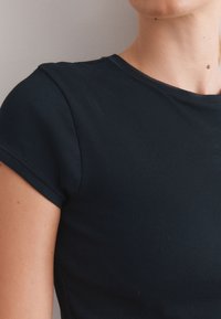 Dark navy ribbed knit t-shirt with short cap sleeves and a round neckline, featuring a plain design and smooth texture.