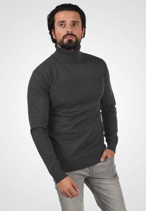 Suéter de cuello alto gris oscuro, tejido de punto, diseño ajustado, cuerpo texturizado, puños acanalados, combinado con jeans gris claro.