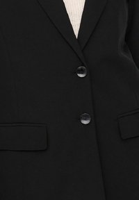 Černý blazer s dvěma předními kapsami a dvěma lesklými knoflíky. Vyroben z hladké tkaniny s strukturovaným designem.