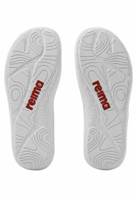 White rubber shoe soles with textured patterns, featuring the red logo "reima." The design includes smooth and ridged sections for grip.