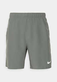 Grå sportshorts med elastisk midja, sidofickor och en vit Nike-logotyp på nedre högra sidan. Lättviktigt tyg.