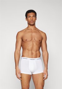Weiße Baumwoll-Boxershorts mit schwarzem Lacoste-Logo am Bund, mit körperbetontem Schnitt und glatter Textur.