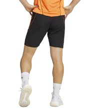 Schwarze Sportshorts mit orangefarbenen Akzenten, aus leichtem Material gefertigt, mit einer enganliegenden Passform, kombiniert mit weißen Socken und hellen Schuhen.