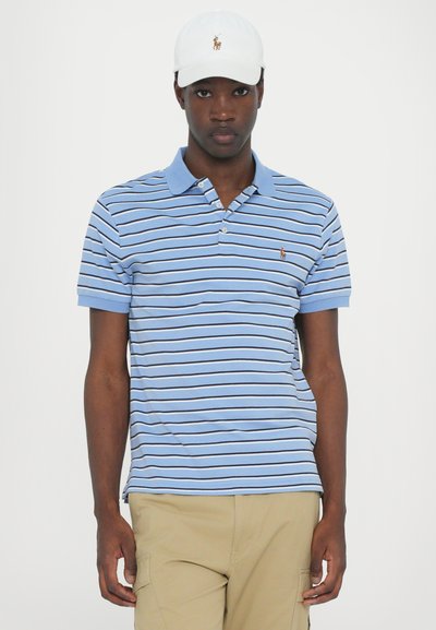 Ανδρική μπλε ριγέ πόλο μπλούζα με γιακά, κοντά μανίκια, λευκές λεπτομέρειες και μικρό κεντημένο λογότυπο στο στήθος. Συνδυάζεται με καμηλό παντελόνια.