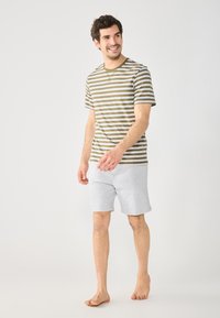 Striped short-sleeve t-shirt in olive and beige, paired with light gray shorts. Material appears soft; casual fit with a crew neck design.