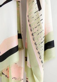 Lightweight scarf featuring a mix of green, pink, and black abstract patterns. Edges are fringed, and fabric appears soft with a smooth texture.