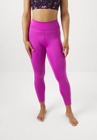 Leggings rosa aderenti con un'alta vita, texture liscia e design alla caviglia. Adatte per abbigliamento sportivo o casual.