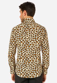 Camicia a maniche lunghe con base beige e stampa leopardata arancione e nera. Colletto classico e polsini con bottoni. Tessuto dalla texture liscia.