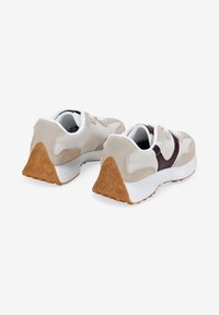 Zapatillas beige y blancas con un acento burdeos, de ante texturizado, piel lisa y una suela de goma que presenta patrones de agarre circulares.