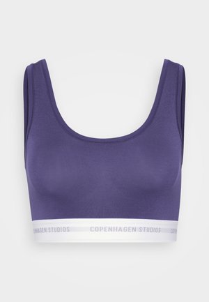 Sujetador deportivo morado con escote en forma de U y tirantes anchos. Presenta una banda blanca contrastante con "COPENHAGEN STUDIOS" impresa en ella.