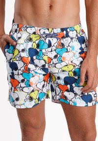 Bañador con un patrón colorido de perros de dibujos animados en azul, naranja, verde y negro sobre un fondo blanco. Cintura elástica con cordón.