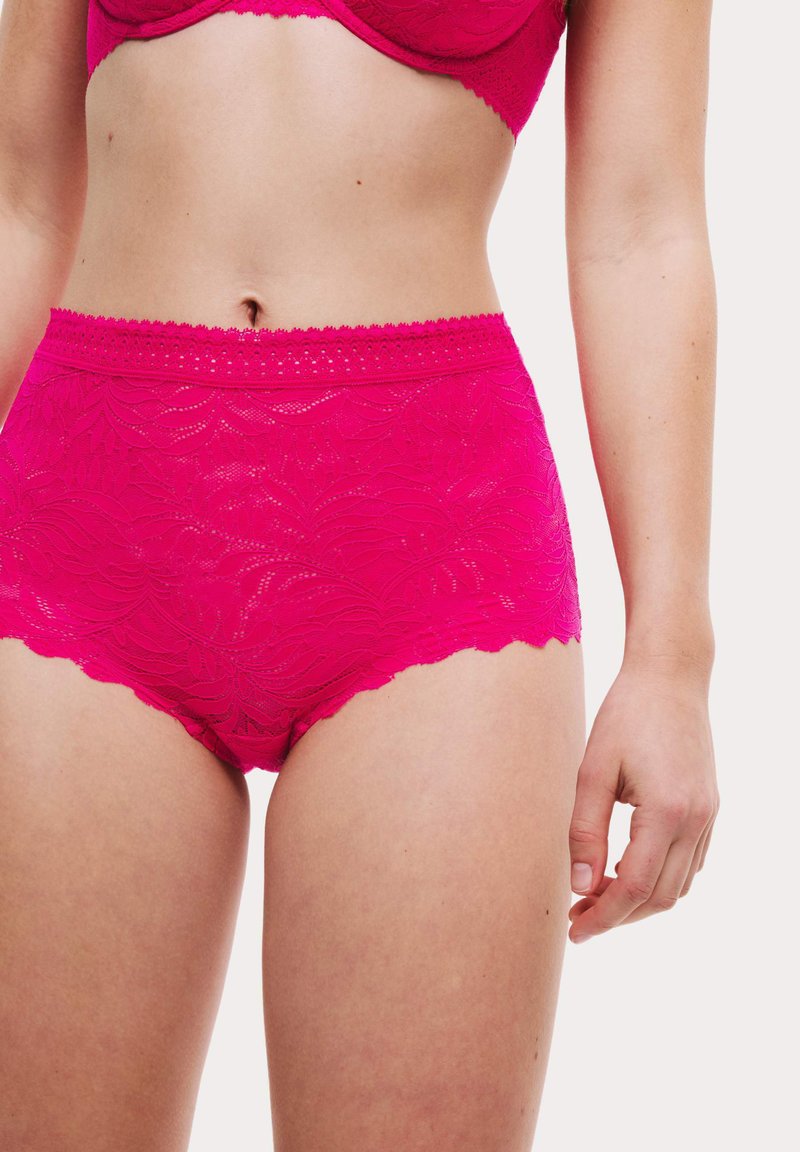 Magenta högmidjade trosor i spets med ett blommönster. Kanterna är vågiga och har en texturerad midjeband med subtila detaljer.