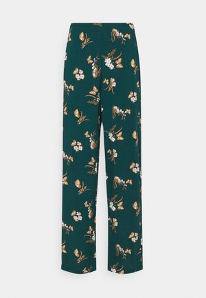 Weite Bein-Hosen aus dunkelgrünem Stoff, mit floralen und Schmetterlingsmustern in Weiß, Rosa und Orange. Leicht und fließend im Design.
