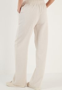 Lichtbeige, wijde broek met een elastische tailleband, voorzien van zijzakken en een zachte textuur, geschikt voor casual draag.