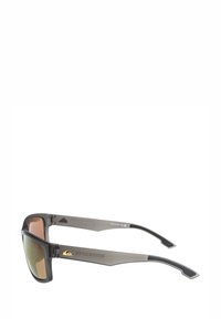 Zonnebril met een matte zwarte frame en bruine gradient lenzen. Bevat gestructureerde veren en het Quiksilver-logo op de slapen.