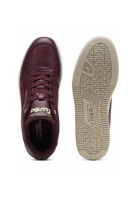 Bordeaux lædersneakers med perforeret tå, hvide snørebånd og en cremefarvet gummisål med tekstureret mønster. Branding på tungen.