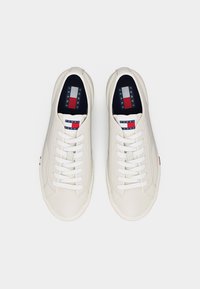 Άσπρα sneakers Tommy Jeans με λευκά κορδόνια και λογότυπο σε κόκκινο, άσπρο και μπλε στη γλώσσα και την εσωτερική σόλα, φαίνονται από πάνω.