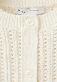 Strickcardigan in Cremefarbe mit vertikalen Mustern, zwei weißen Knöpfen und einem sichtbaren MNG-Kleidungsgrößenetikett EU-USA S/MEX CH.