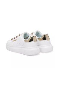 Sneaker bianchi con tomaia in pelle liscia, tacco con accenti dorati e lacci marroni. Presentano una spessa suola in gomma bianca e dettagli cuciti.