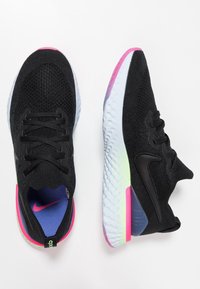 Černé sportovní boty s texturovaným pleteným svrškem, s růžovými akcenty na patě a podrážce, a světle modrou gumovou podrážkou.