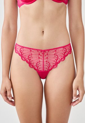 Tanga rosa brillante con detalles de encaje, con un borde festoneado y un patrón floral. Fabricada con un material transparente para un aspecto delicado.