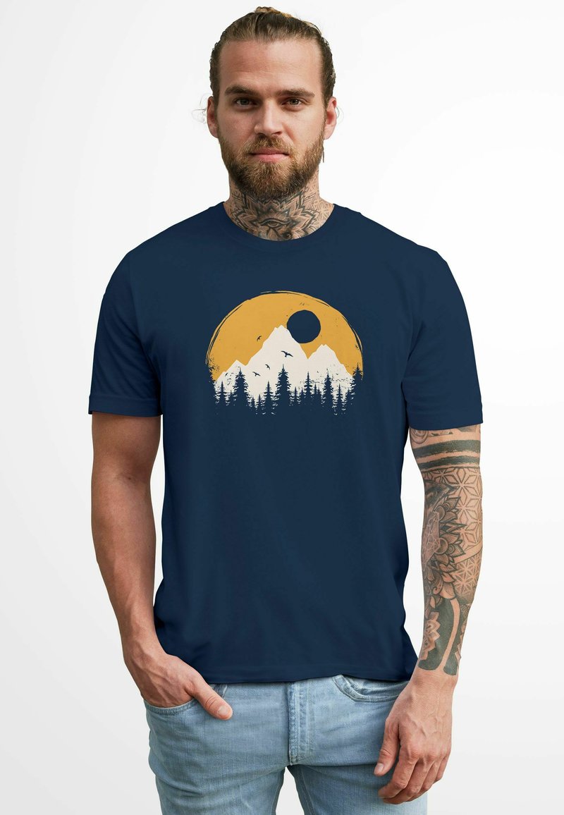 T-Shirt mit kurzen Ärmeln in Marineblau, das eine Grafik von Bergen und Wäldern in Gelb und Weiß zeigt, mit einer kreisförmigen Sonne und Vögeln im Flug.