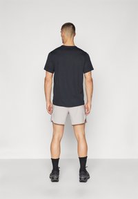 Black short-sleeve shirt, grey athletic shorts, black socks, and black shoes. Simple, form-fitting design with a clean cut.