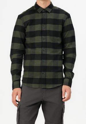 Chemise à carreaux vert et noir, à manches longues, avec un col classique et des boutons noirs à l'avant. Matière en coton.