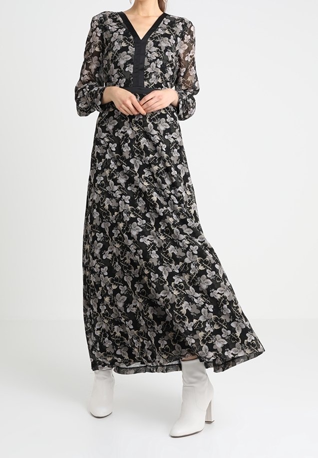 Maxi sukienka z czarnym kwiatowym wzorem, przezroczystymi długimi rękawami, dekoltem w kształcie litery V i dopasowanym torsie. W zestawieniu z białymi botkami za kostkę.