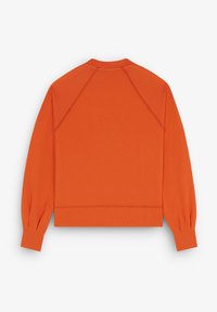 Sweatshirt court orange avec des manches raglan, texture douce, col et poignets côtelés, arborant un design épuré et minimal.