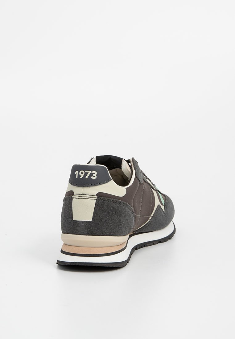 Zapatillas para hombre en gris y crema, con materiales de ante y malla, punta redonda, suela acolchada y un destacado detalle de "1973" en el talón.