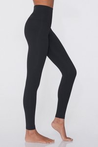 Leggings noirs taille haute en matériau extensible, offrant une texture lisse et un design sans coutures, s'étendant jusqu'aux chevilles.