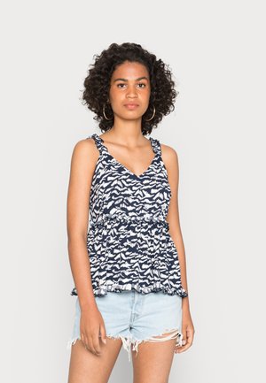 Top de tanque com padrão azul-marinho e alças com babados, decote em V e cintura elástica. Combinado com calções de ganga claros e desgastados.