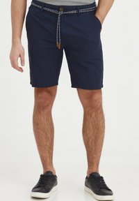Navy blue shorts with a woven white drawstring, button closure, and side pockets. Fabric appears lightweight and casual.