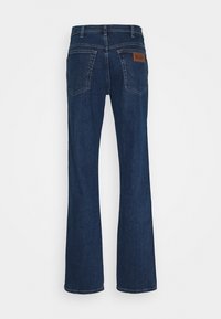 Mörkblå utsvängda jeans i kraftig denim. Har två bakfickor och en läderetikett på midjebandet. Ren sömnad.
