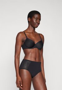 Black bra with smooth cups and adjustable straps, paired with high-waisted black panties featuring sheer side panels.