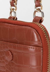 Borsa a tracolla in finta pelle marrone con texture a coccodrillo, accessori in oro e una robusta cerniera. Include una tracolla intrecciata per un tocco di dettaglio in più.