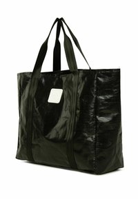 Iso suur must käsipagas, mis on valmistatud läikivast kangast, kahele lamedale käepidemele, nelinurkse kujuga ja valge sildiga aksessuaardina.