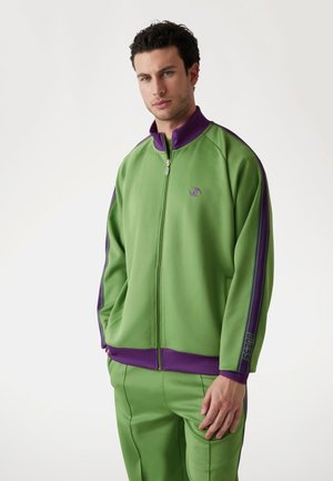 Green zip-up track jacket with purple accents and logo, featuring a relaxed fit and smooth texture. Pairing with matching green pants.