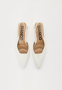 White patent leather slingback heels with pointed toes, padded insoles, and cutout sides. 'BIANCO' logo printed on the insoles.