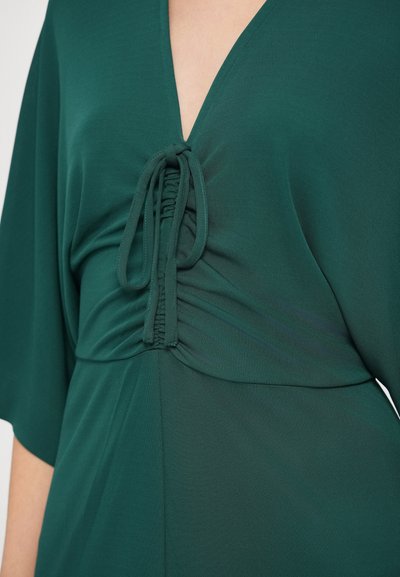 Πράσινο φόρεμα με βαθύ V-λαιμόκοψη, διαθέτει πτυχές υφάσματος και ρυθμιζόμενο κορδόνι στη μέση. Μαλακό, υφασμάτινο με υφή και φαρδιά μανίκια που ρέουν.