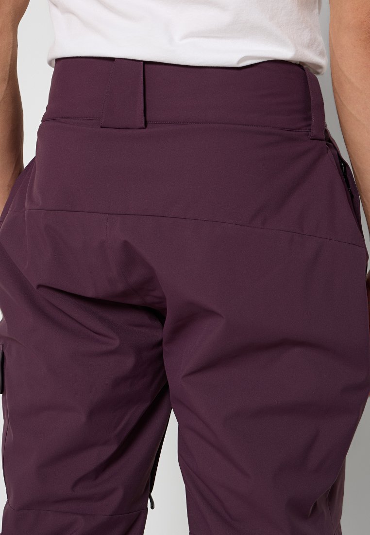 Pantaloni a vita alta viola realizzati in un materiale liscio e resistente all'acqua. Presentano una parte anteriore piatta e una tasca laterale discreta. Design con cintura elastica.