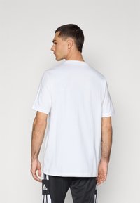 Wit katoenen T-shirt met korte mouwen en een ronde hals, gezien vanaf de achterkant. Heeft een minimalistisch ontwerp, zonder zichtbare logo's of patronen.